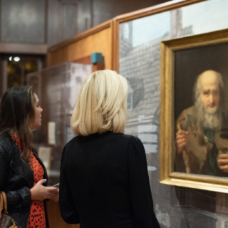 Two women looking at a painting and graphics in a museum exhibition